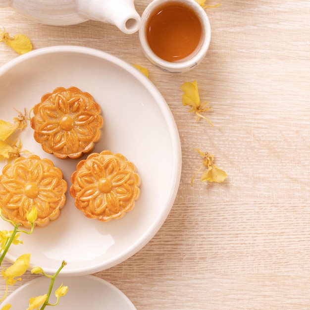 Delicioso pastel de luna para el festival MidAutumn con un hermoso patrón decorado con flores amarillas y té Concepto de diseño de pastelería festiva por la tarde