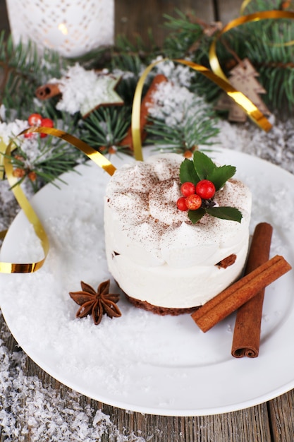 Delicioso pastel en plato con canela y anís estrellado en decoración navideña