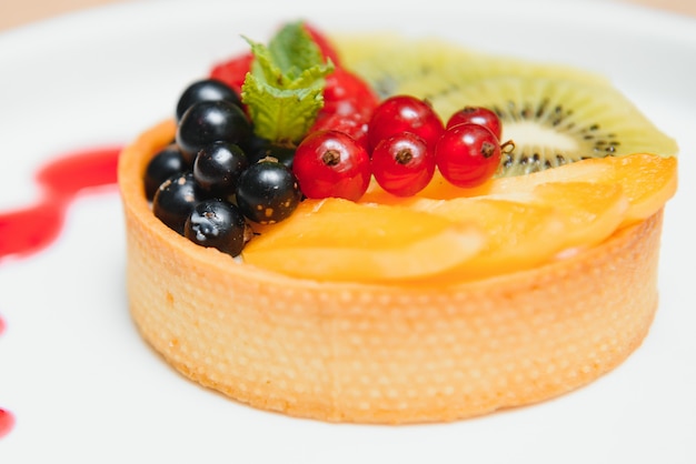 Foto delicioso pastel de queso con frutos rojos en la mesa de cerca