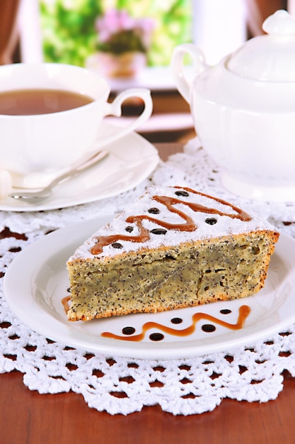 Delicioso pastel de semillas de amapola con taza de té en la mesa en la habitación