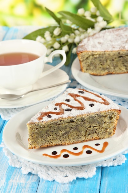 Delicioso pastel de semillas de amapola con taza de té en la mesa sobre fondo brillante