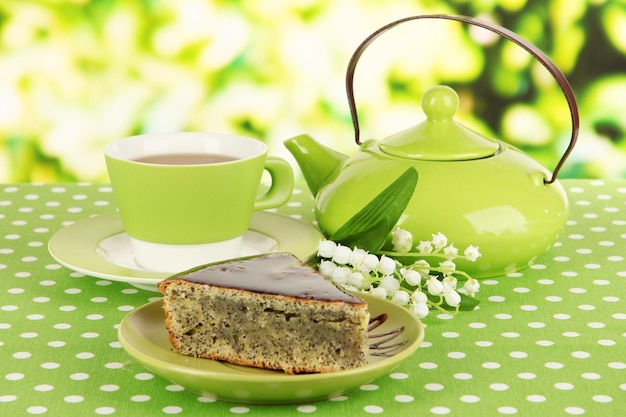 Delicioso pastel de semillas de amapola con taza de té en la mesa sobre fondo brillante