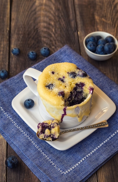 Delicioso pastel de taza de muffin de arándanos casero con bayas frescas sobre fondo de madera rústica