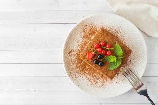 Delicioso pastel de tiramisú con bayas frescas y menta en un plato o