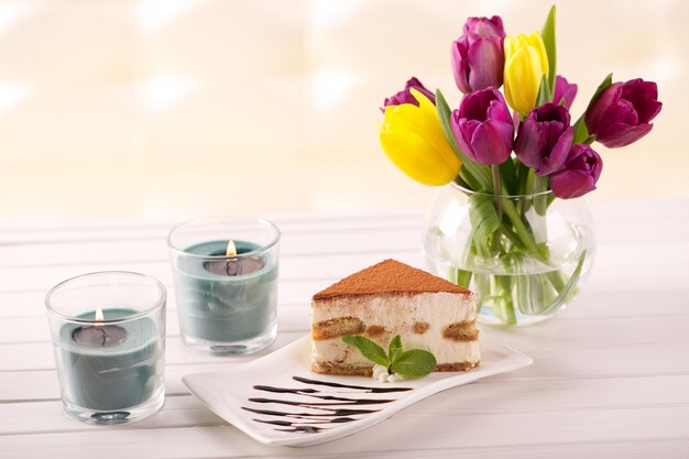 Delicioso pastel de tiramisú y flores de tulipán como regalo