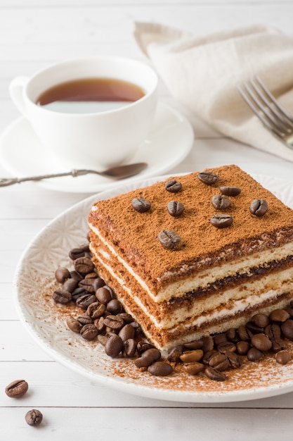 Delicioso pastel de tiramisú con granos de café en un plato y una taza o