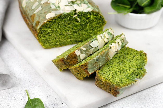 Delicioso pastel verde con espinacas y almendras cortadas en tablero de mármol