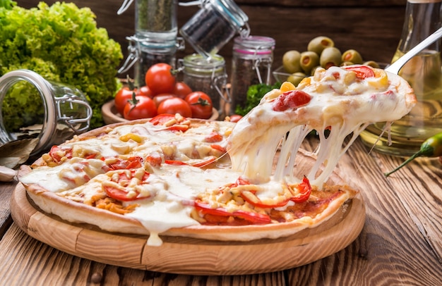 Delicioso pedaço de pizza quente na bandeja de madeira com queijo derretido