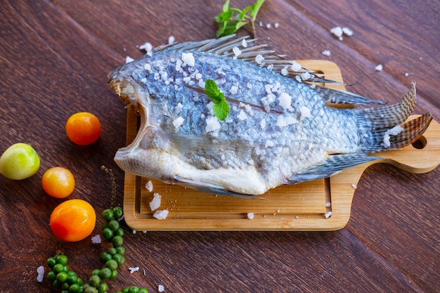 Delicioso peixe fresco em fundo escuro. peixe com ervas aromáticas, dieta ou conceito de culinária