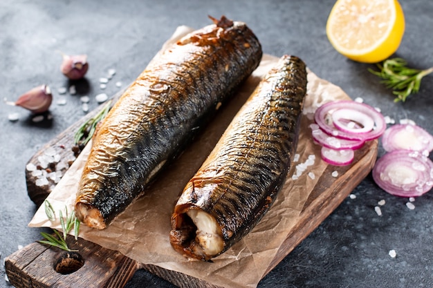 Delicioso pescado caballa ahumado sobre papel con ajo y aros de cebolla.