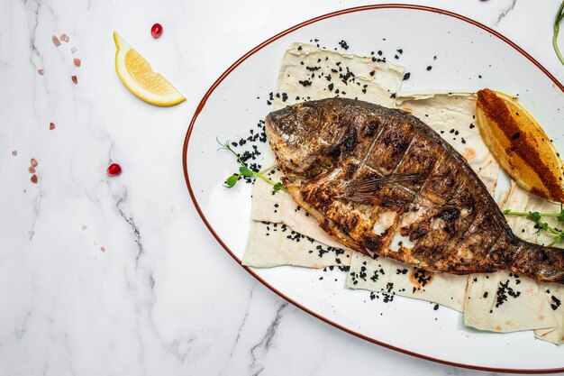 Delicioso pescado dorado a la parrilla con limón y perejil Besugo entero a la barbacoa al horno Parrilla de dorado Almuerzo de dieta cetogénica o paleo Tendencia de comida saludable Vista superior