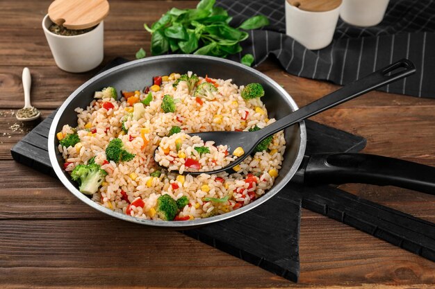 Delicioso pilaf de arroz con brócoli en la sartén sobre una mesa de madera