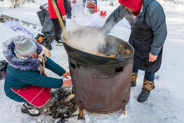 Delicioso pilaf é cozido em um grande caldeirão ao ar livre em um dia de inverno