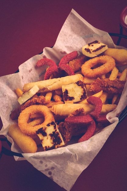 Delicioso plato de bocadillos papas fritas aros de cebolla rollitos de primavera o salchichas en la mesa