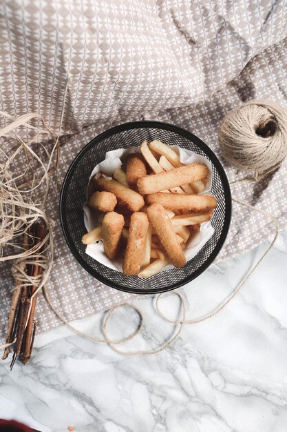 Delicioso plato de bocadillos papas fritas aros de cebolla rollitos de primavera o salchichas en la mesa