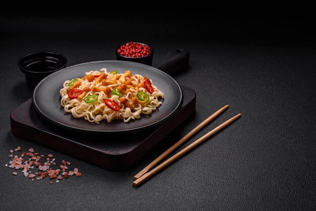 Delicioso plato de cocina asiática con fideos de arroz, pimientos, champiñones y especias sobre un fondo de hormigón oscuro