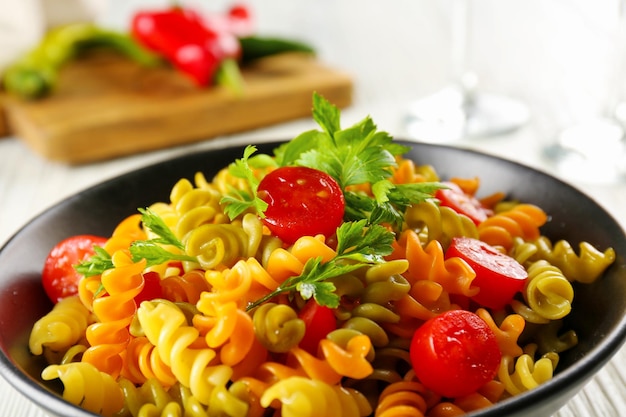 Delicioso plato de macarrones en un tazón negro sobre la mesa de madera gris servida