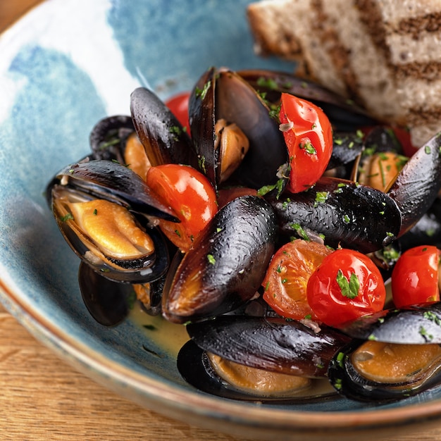 Delicioso plato de pescado italiano elaborado con mejillones y vino blanco sobre la mesa, que se sirve en un restaurante, concepto de comida de menú