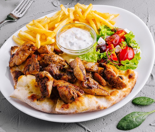 Delicioso pollo a la parrilla y salchichas con ensalada fresca y papas fritas