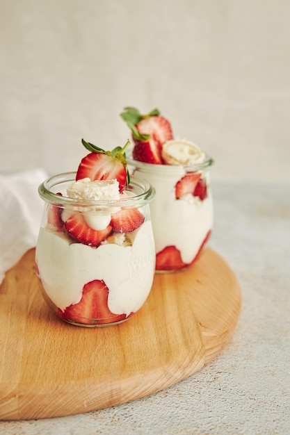 Foto delicioso postre de crema con trufas de coco y fresas sobre una tabla redonda de madera