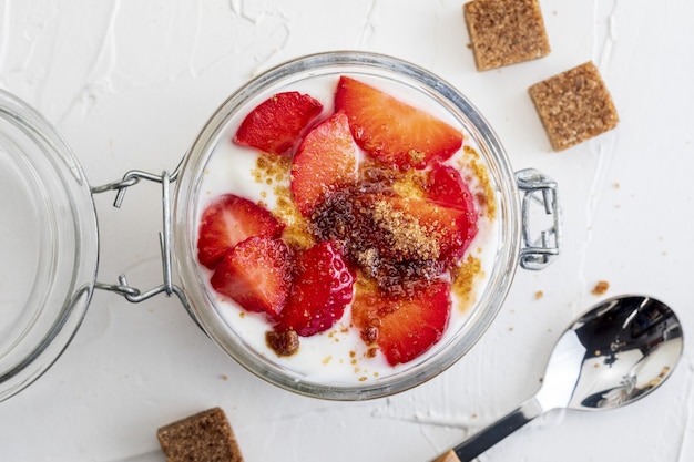 Delicioso postre de fresas, yogur y cereales con azúcar.