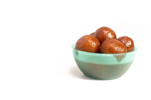 Delicioso postre de Gulab jamun en un cuenco verde sobre un fondo blanco dulces indios