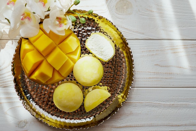 Delicioso postre Mochi con fruta de mango sobre fondo de madera de cerca