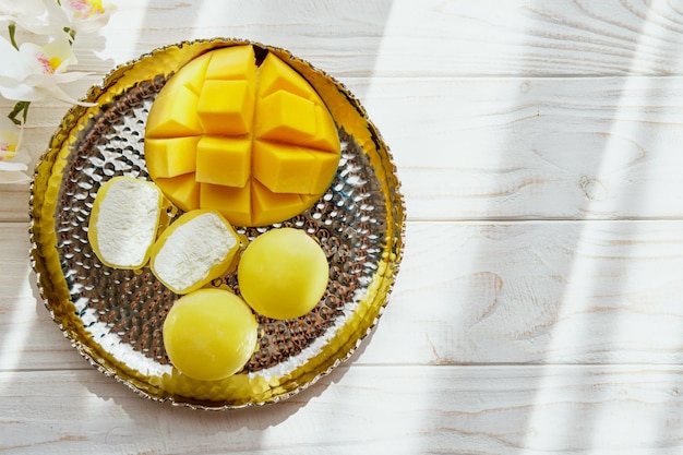 Delicioso postre Mochi con fruta de mango sobre fondo de madera de cerca