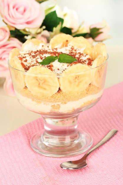 Delicioso postre con plátano y caramelo en la mesa sobre fondo claro