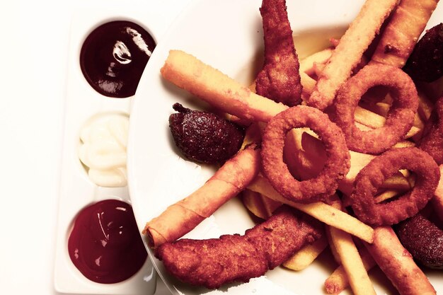 Delicioso prato de lanche batatas fritas anéis de cebola rolinhos primavera ou salsichas na mesa