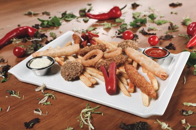 Delicioso prato de lanche batatas fritas anéis de cebola rolinhos primavera ou salsichas na mesa