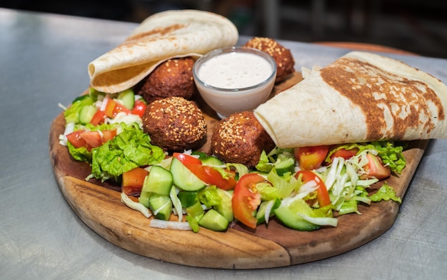 Delicioso prato Falafel em uma placa de madeira closeup tortilha salada de legumes e molho de tahine