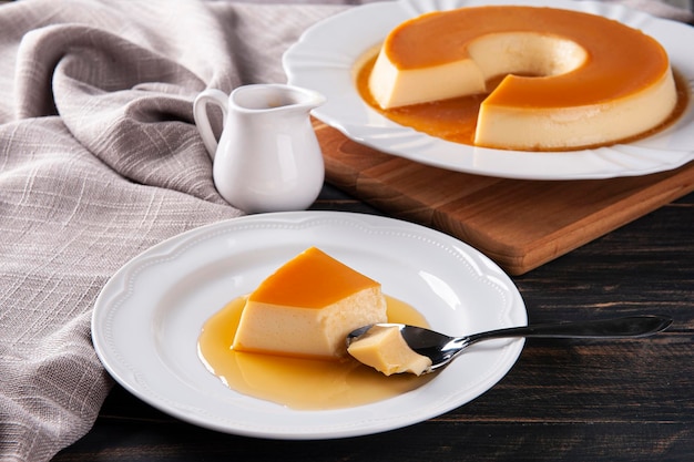 Delicioso pudín de leche condensada en un plato blanco Alguien recogiendo un trozo con una cuchara