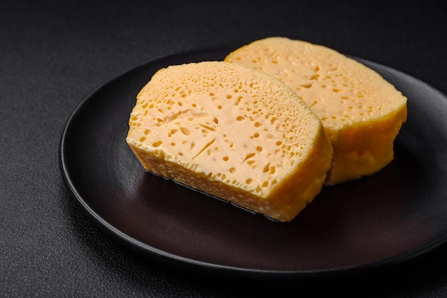 Delicioso queijo amarelo poroso cortado em pedaços grandes em uma placa de cerâmica