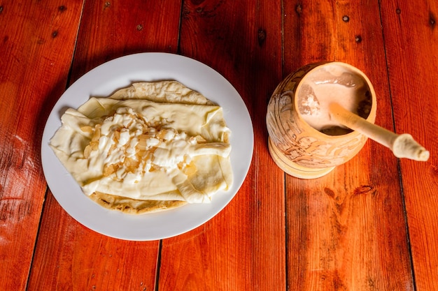 Foto delicioso quesillo tradicional con bebida de cacao plato de quesillo con bebida de cacao servido en mesa de madera comida y bebidas típicas de nicaragua