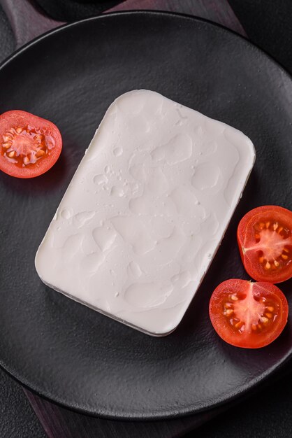 Delicioso queso feta fresco de forma rectangular con especias y verduras