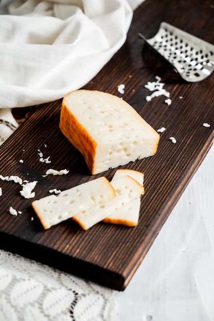 Foto delicioso queso gouda holandés con bloques de queso sobre una vieja mesa de madera blanca.