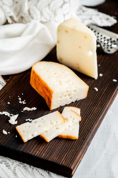 Foto delicioso queso gouda holandés con bloques de queso sobre una vieja mesa de madera blanca.