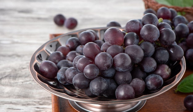 Delicioso racimo de uvas en un plato sobre fondo de mesa de madera.