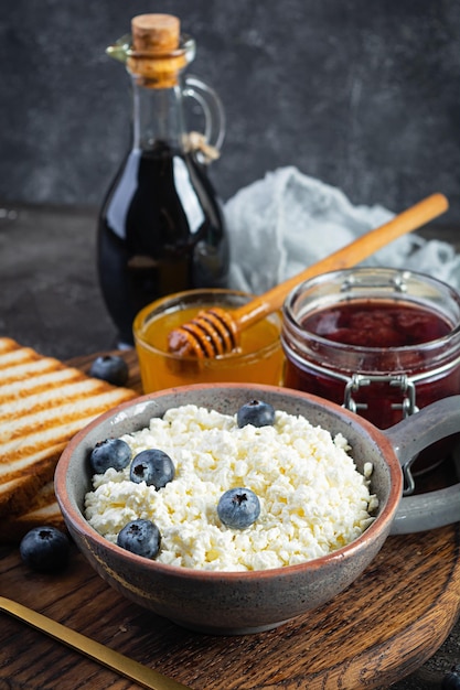 Delicioso requesón con arándanos, miel, mermelada de fresa y tostadas. Desayuno saludable