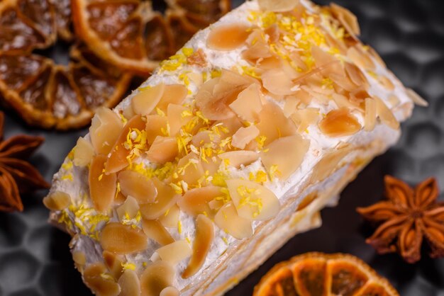 Delicioso rollo de merengue dulce fresco con chips de almendras crema, nueces y bayas cortadas en rodajas sobre un fondo de hormigón oscuro