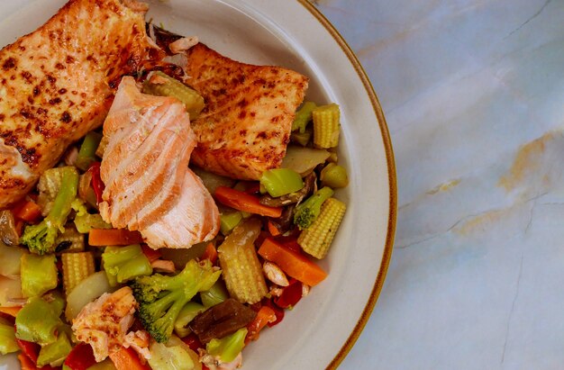 Delicioso salmón a la plancha con verduras salteadas asiáticas en un plato. Copie el espacio.