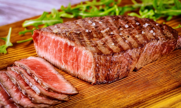 Delicioso y saludable bistec a la parrilla medio raro sobre tabla de madera