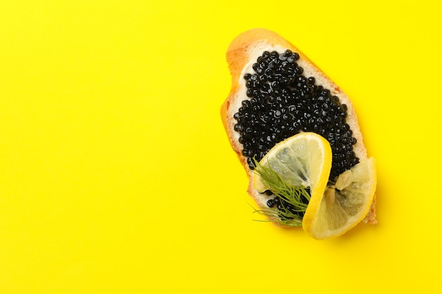 Delicioso sanduíche com caviar preto em fundo amarelo