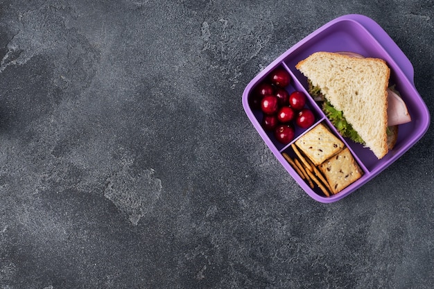 Delicioso sanduíche saudável em uma lancheira, biscoitos e cerejas. Leve o almoço com você para a escola ou para o escritório.