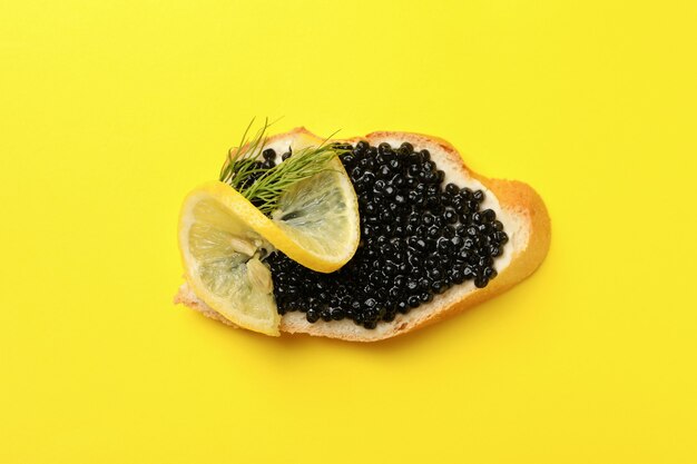 Delicioso sándwich con caviar negro sobre fondo amarillo