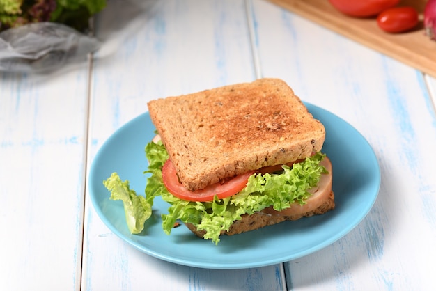 Delicioso sándwich con jamón y lechuga fresca en el plato.