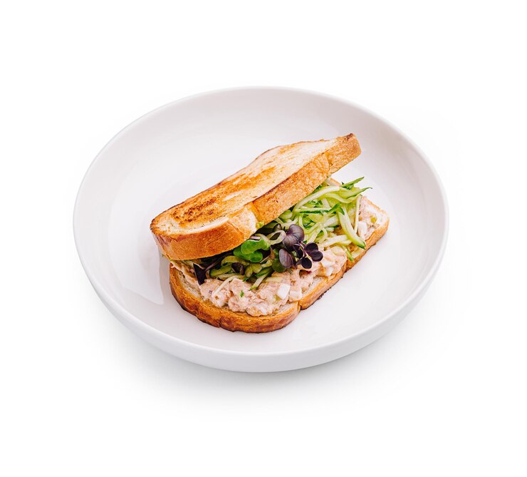 Delicioso sándwich con pan tostado lleno de verduras frescas y salada de pollo salada para una comida satisfactoria