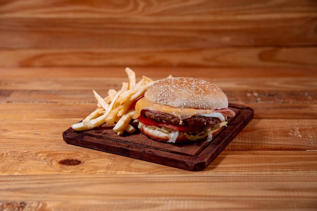 Delicioso sándwich con papas fritas sobre fondo de madera