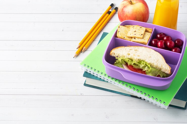 Delicioso sándwich saludable en lonchera, galletas y cerezas. Lleve el almuerzo a la escuela oa la oficina. Jugo en botella y manzana.